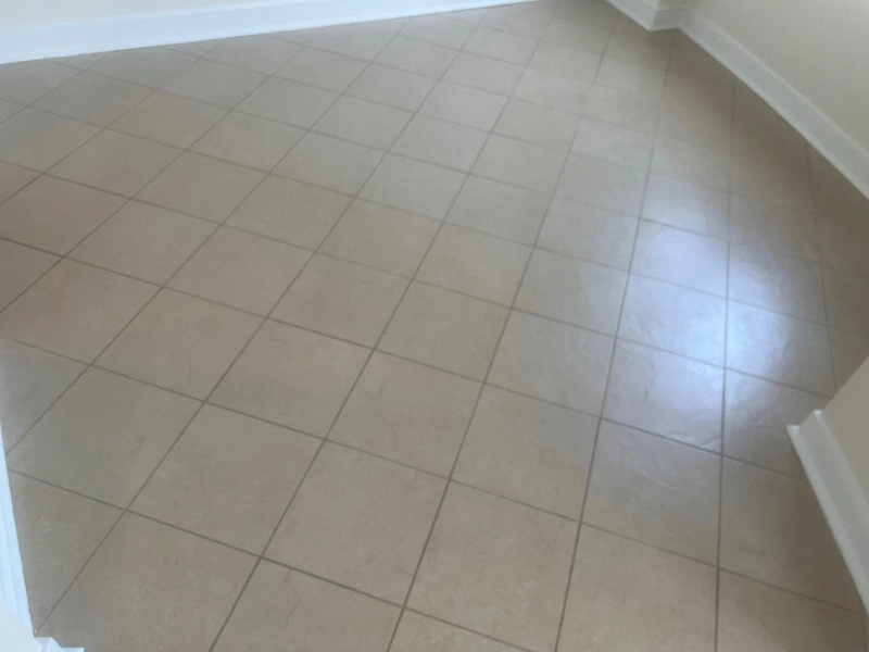 Empty room with beige square tiled floor and white baseboards.
